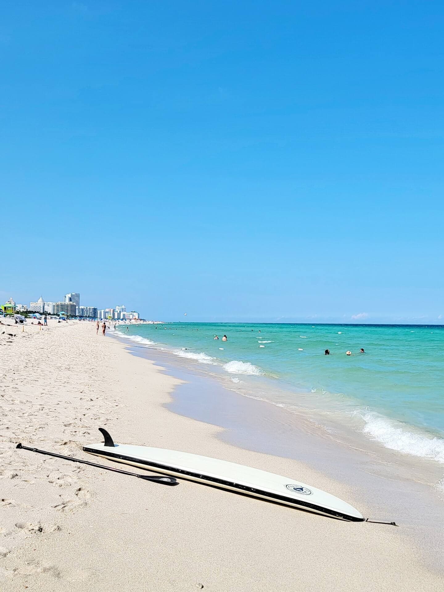 South Beach shoreline with a paddleboard on the sand and the Miami Beach skyline in the distance